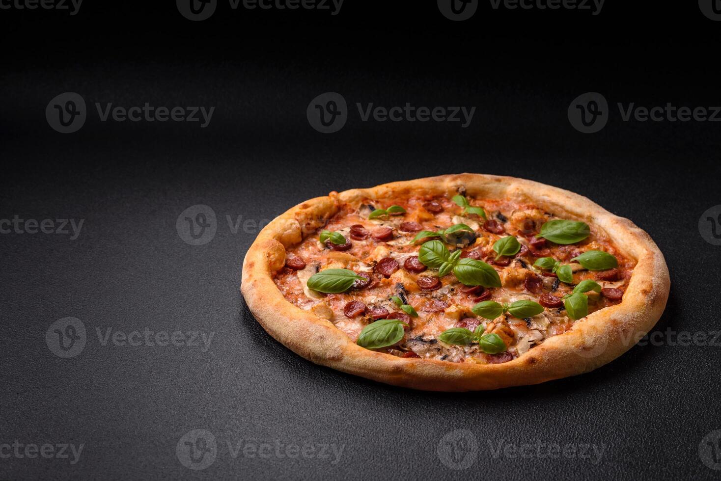 Delicious pizza with sausage, cheese, tomatoes, salt, spices and herbs photo