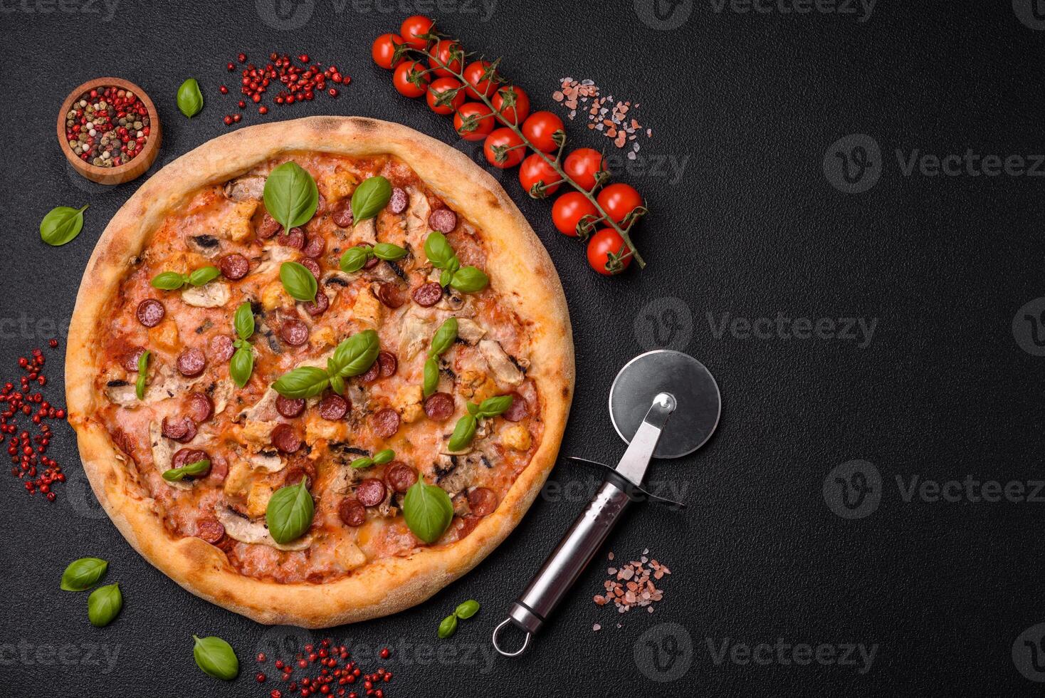 Delicious pizza with sausage, cheese, tomatoes, salt, spices and herbs photo