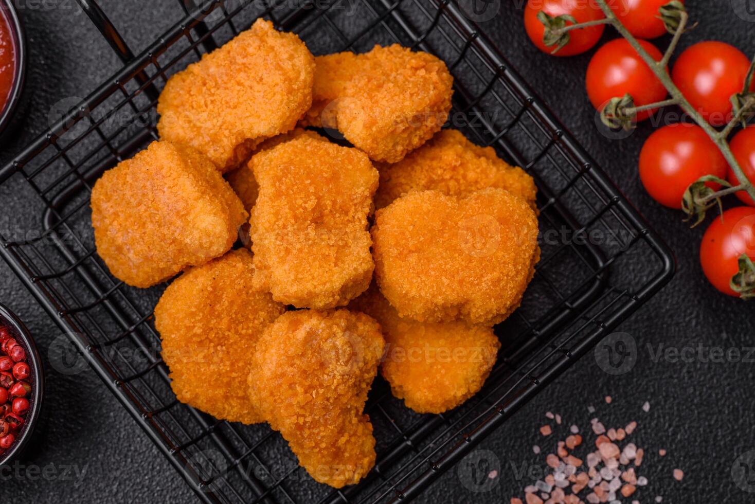 Delicious fresh crispy chicken nuggets on a dark concrete background photo