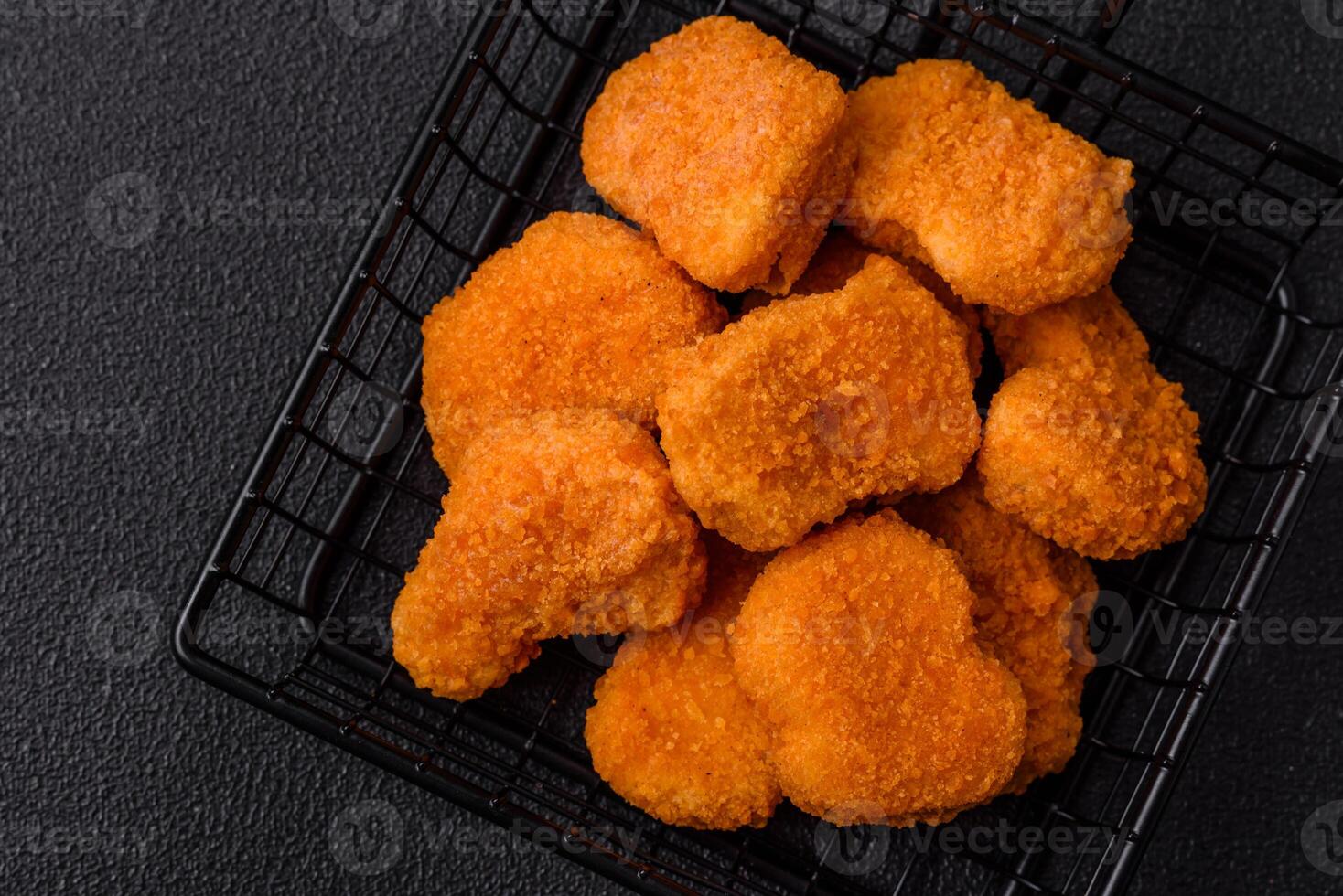 Delicious fresh crispy chicken nuggets on a dark concrete background photo