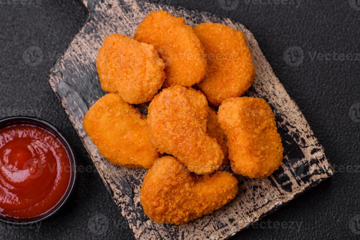 Delicious fresh crispy chicken nuggets on a dark concrete background photo