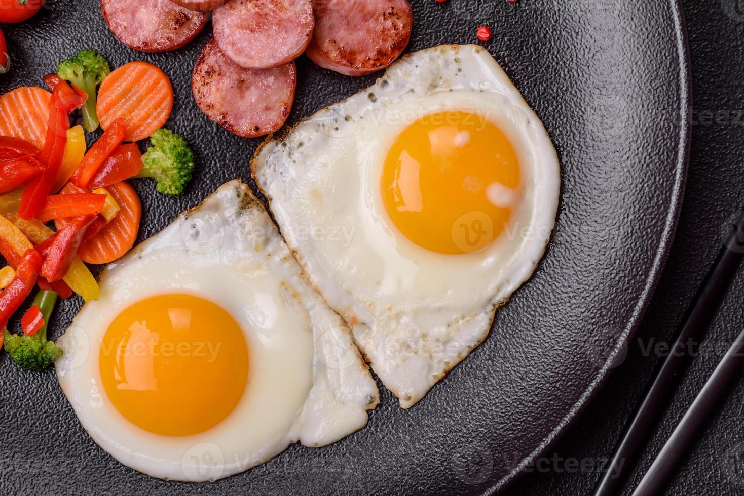 Delicious nutritious breakfast with fried eggs, sausage, steamed vegetables photo