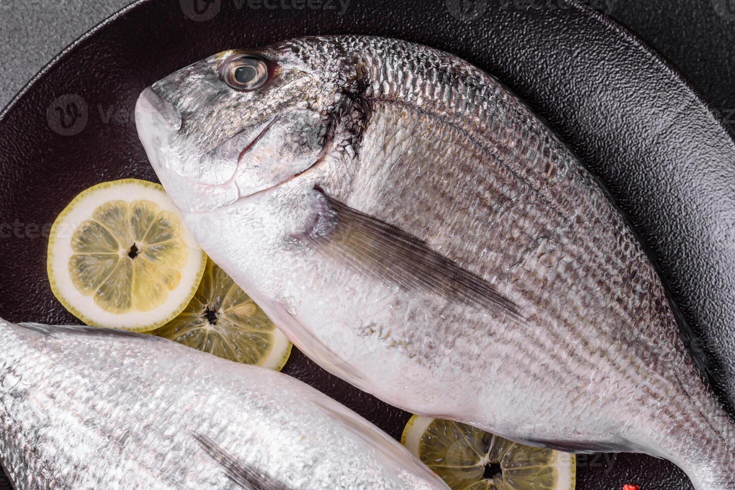 Whole raw dorado fish with lemon, salt, spices and herbs photo