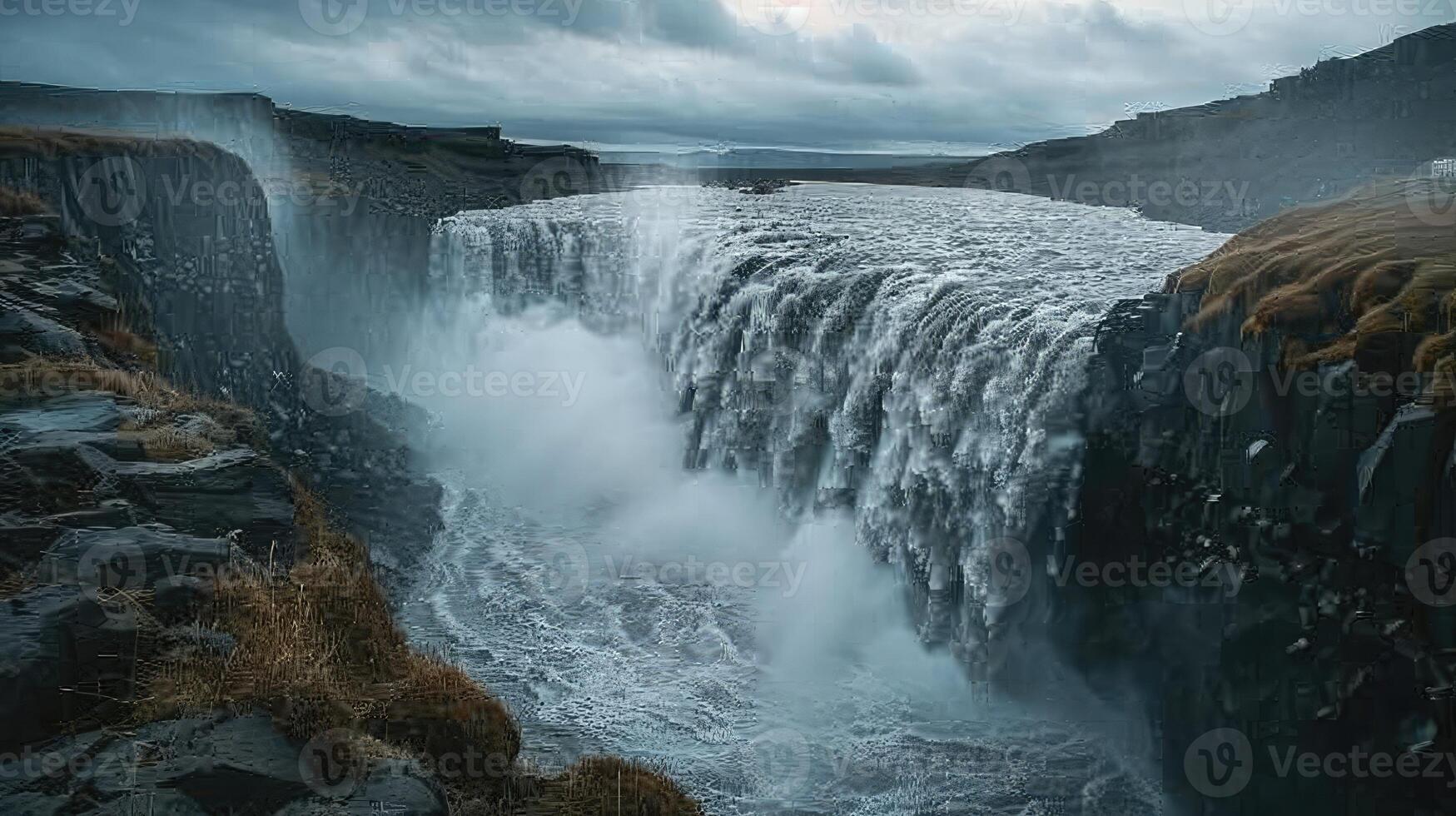 a waterfall is flowing over a cliff under a cloudy sky photo