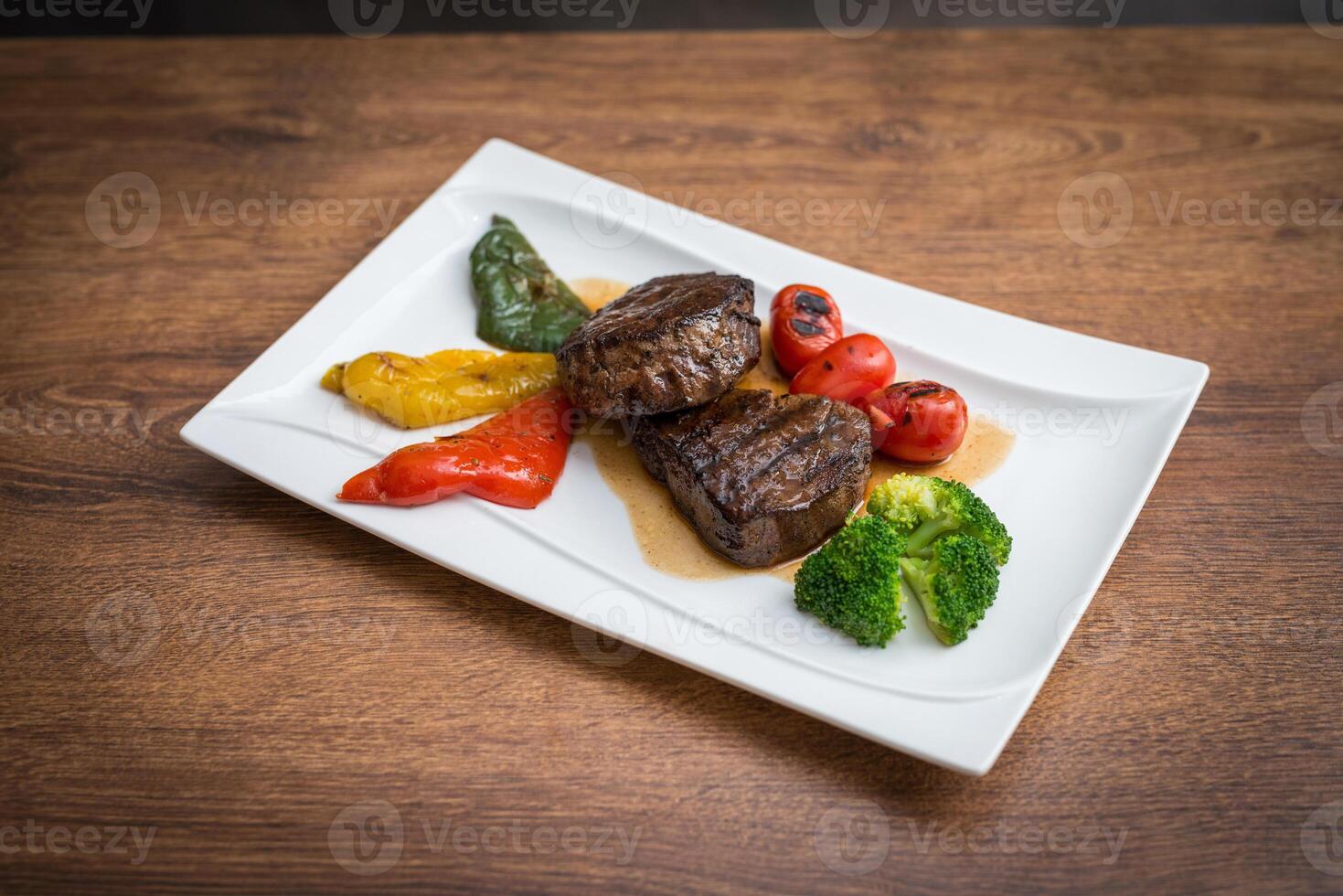 Steak with grilled vegetables and seasoning on serving plate photo
