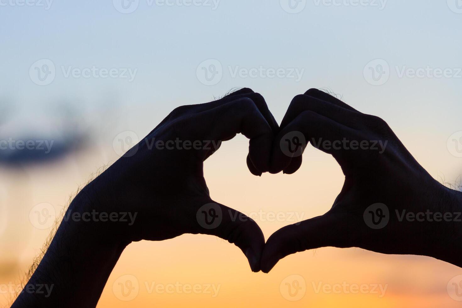 Love sign. Heart symbol by hand silhouette in sunset sky. Vintage style. photo