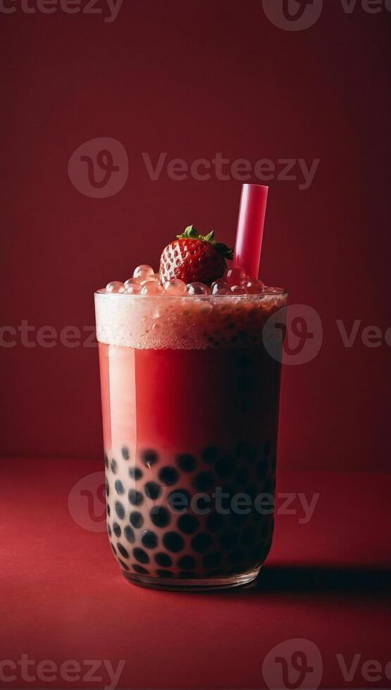 Refreshing strawberry bubble tea with tapioca pearls visible at the bottom in the glass with straw. Studio shot on the red background photo