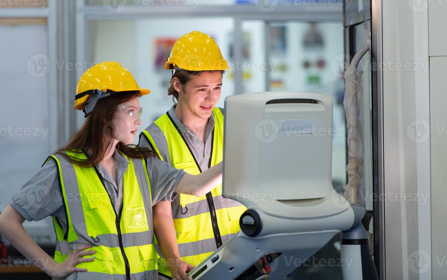 Both of young factory worker wearing a hard hat looking at a computer screen used to control production. photo