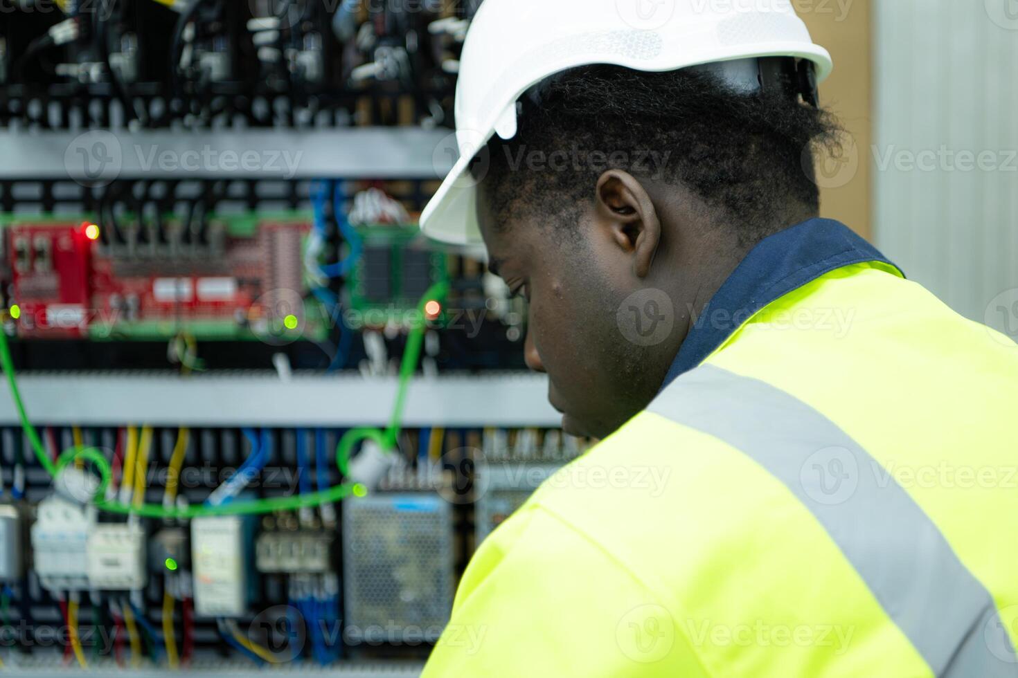 Portrait of a technician working with a digital multimeter to test the electrical system of a huge circuit board at an industrial plant using an automated hand robot. photo