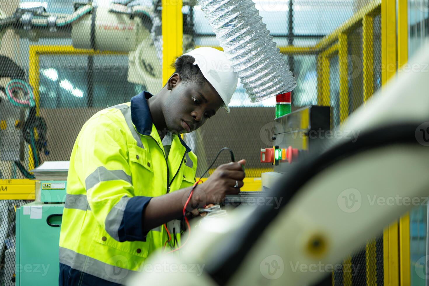 Portrait of a technician working with a digital multimeter to test the electrical system of a huge circuit board at an industrial plant using an automated hand robot. photo