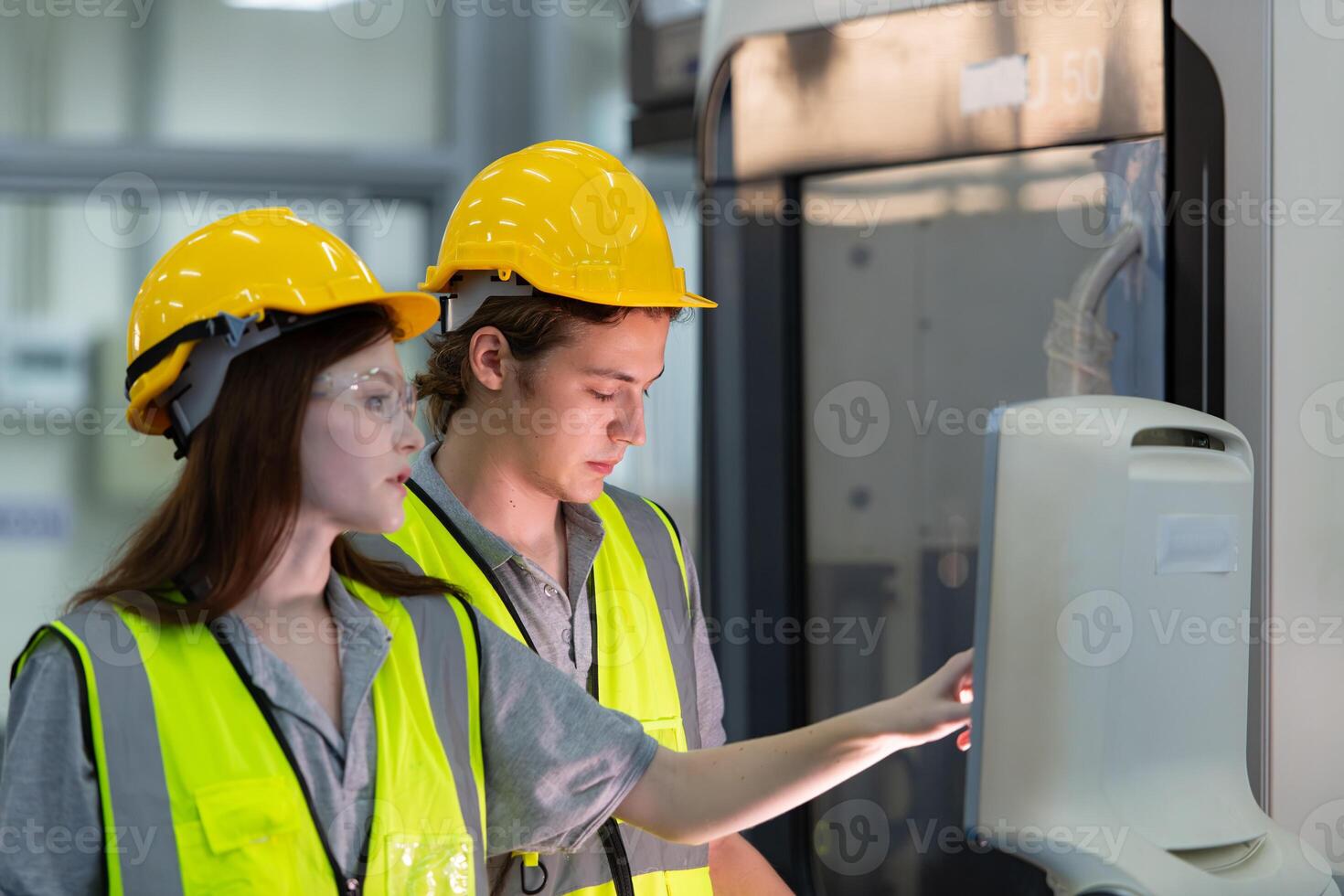 Both of young factory worker wearing a hard hat looking at a computer screen used to control production. photo