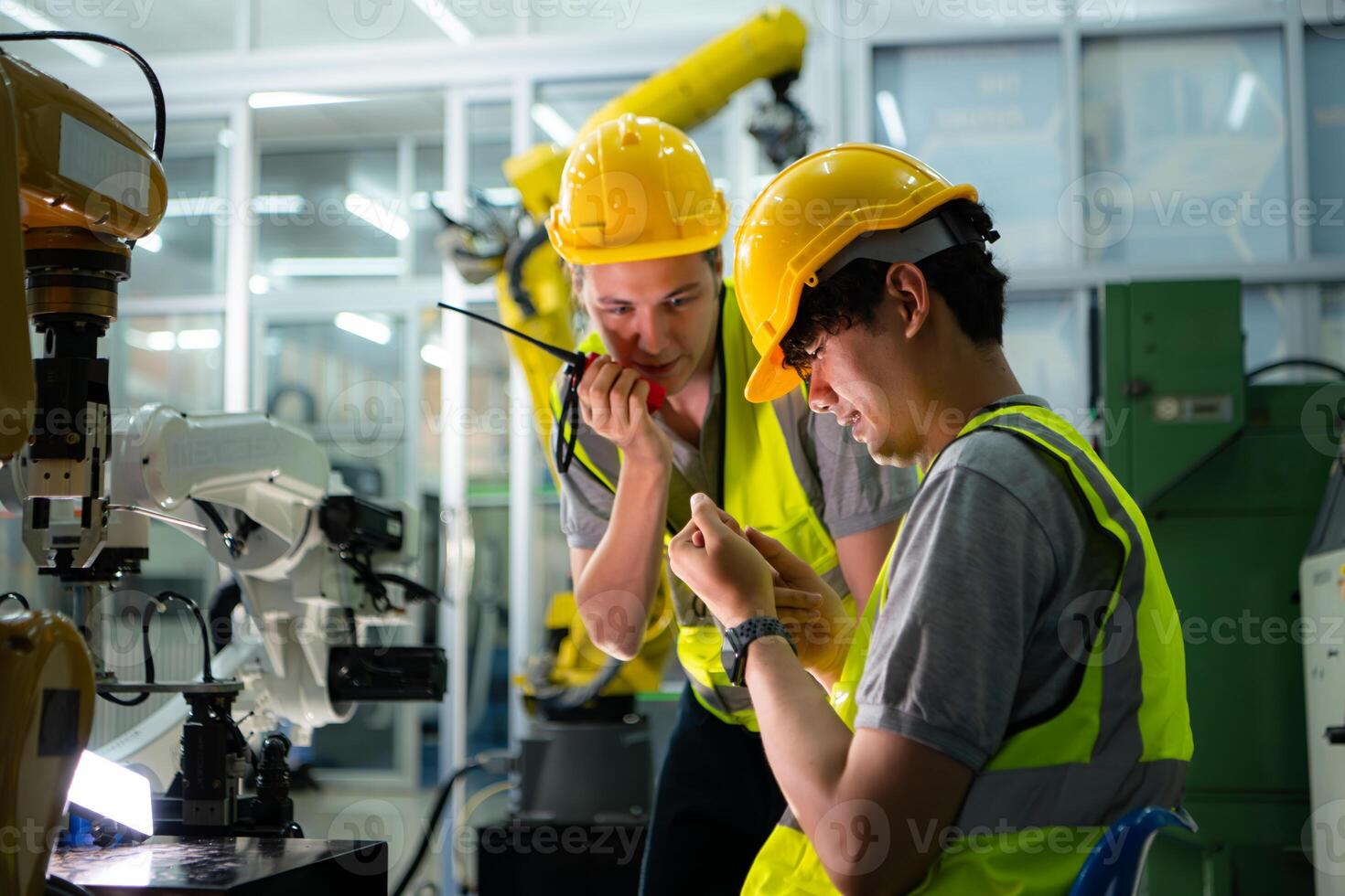 A technician suffers a hand accident while working with a robot arm in a factory with co-workers providing assistance photo