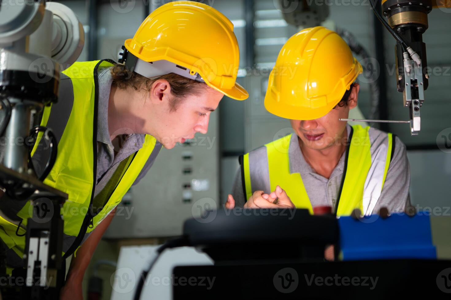 A technician suffers a hand accident while working with a robot arm in a factory with co-workers providing assistance photo