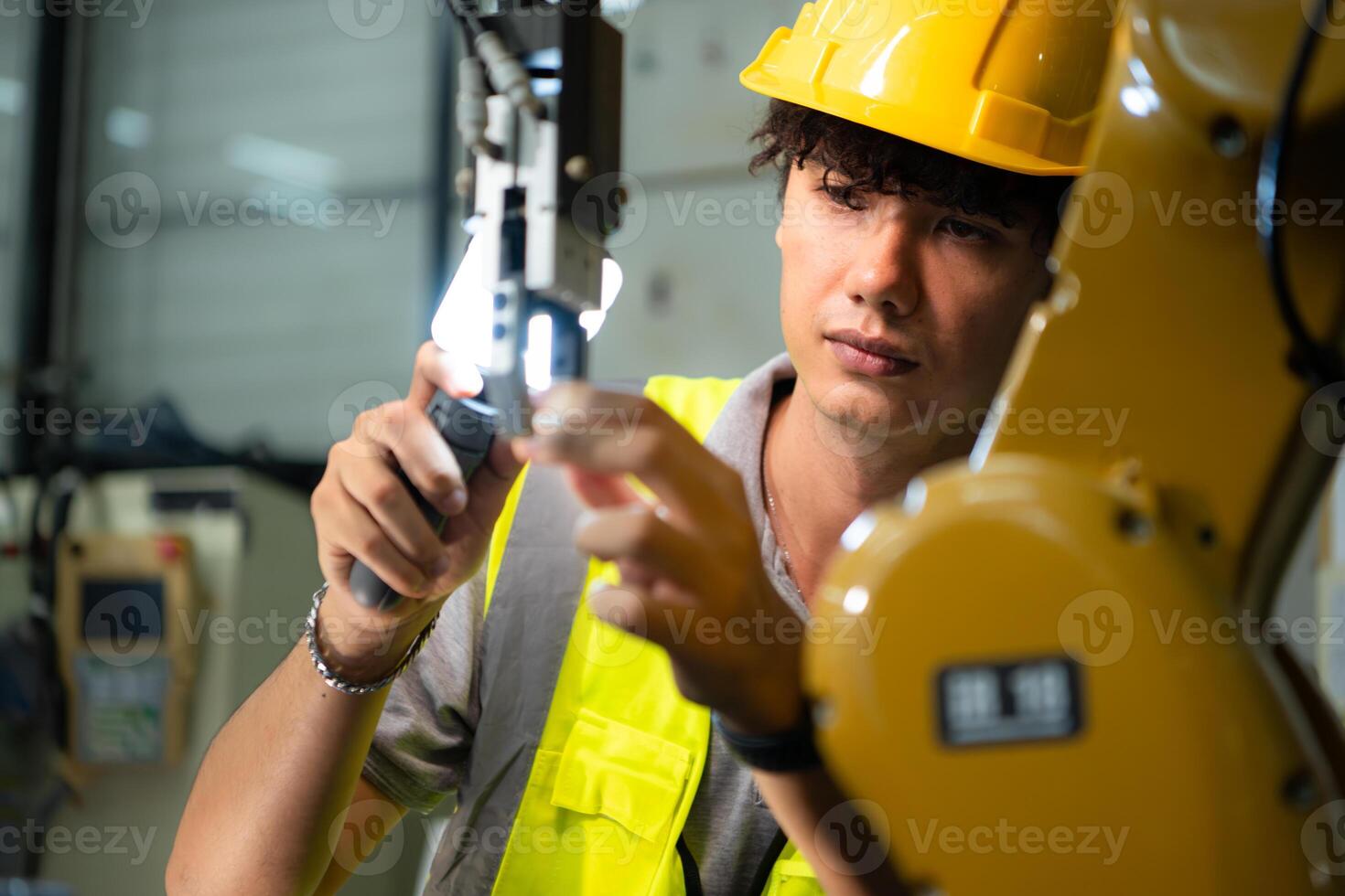 Technician who maintains a small robot arm the operation of a small robot arm used in industry is being repaired. photo