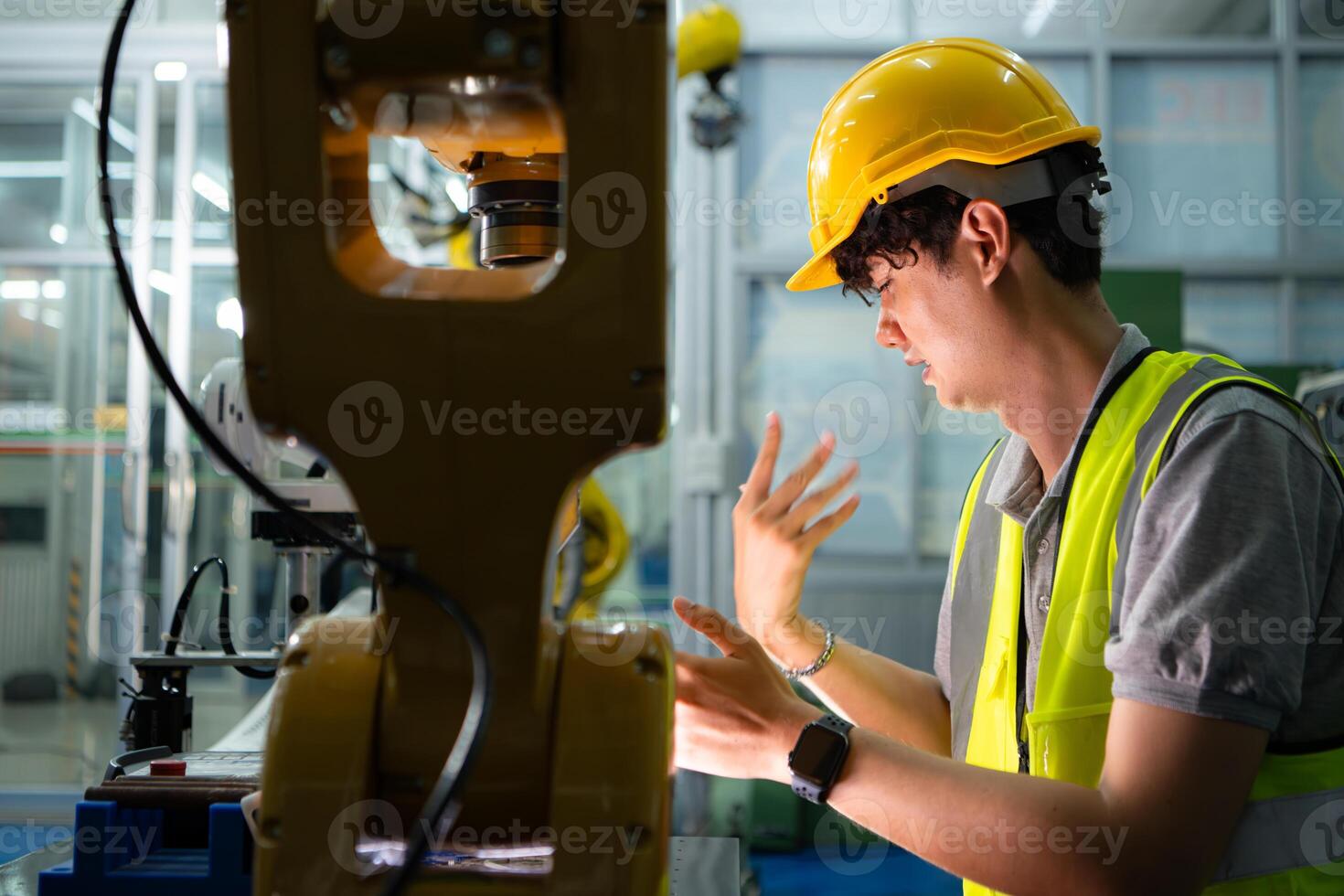 A technician suffers a hand accident while working with a robot arm in a factory with co-workers providing assistance photo