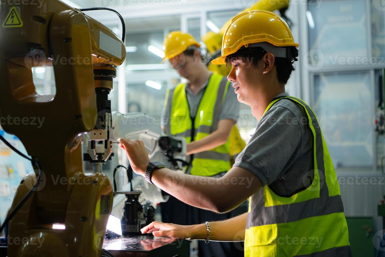 A technician suffers a hand accident while working with a robot arm in a factory with co-workers providing assistance photo