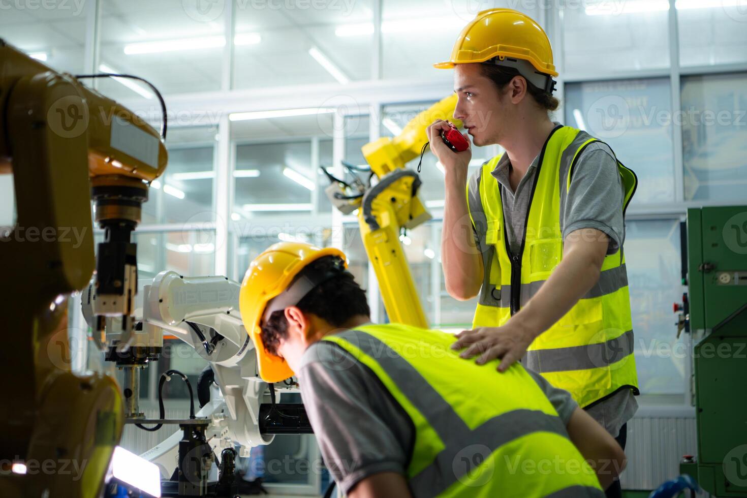 A technician suffers a hand accident while working with a robot arm in a factory with co-workers providing assistance photo