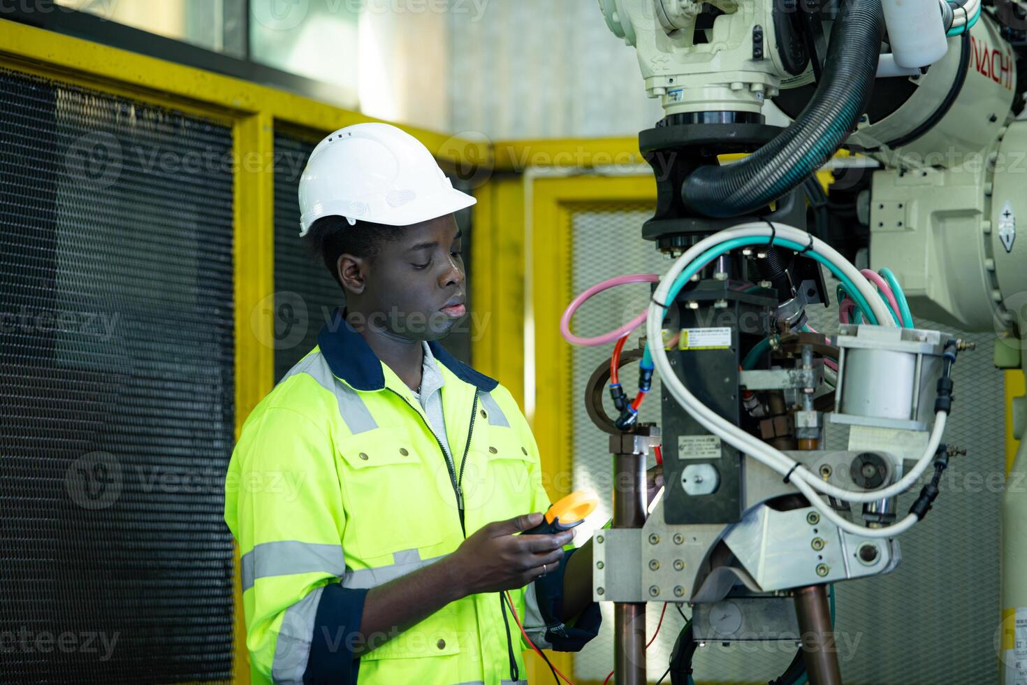 Portrait of a technician working with a digital multimeter to test the electrical system of a huge circuit board at an industrial plant using an automated hand robot. photo