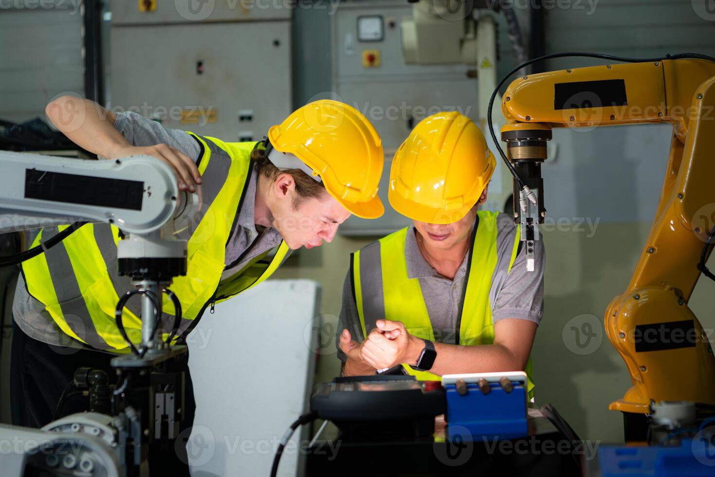 A technician suffers a hand accident while working with a robot arm in a factory with co-workers providing assistance photo