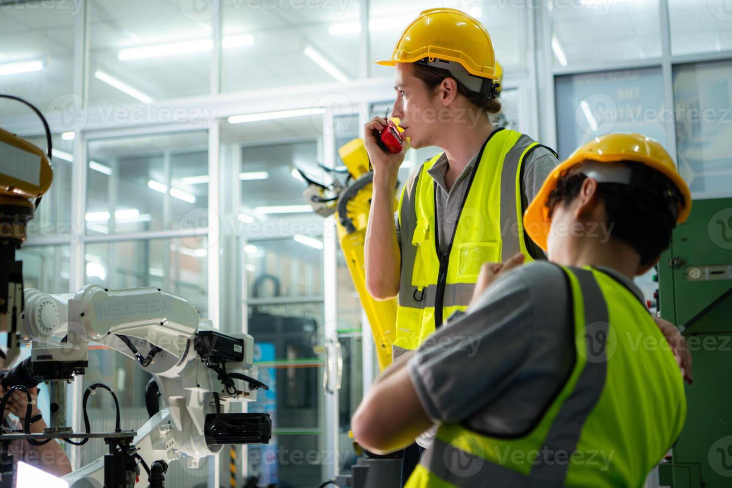 A technician suffers a hand accident while working with a robot arm in a factory with co-workers providing assistance photo