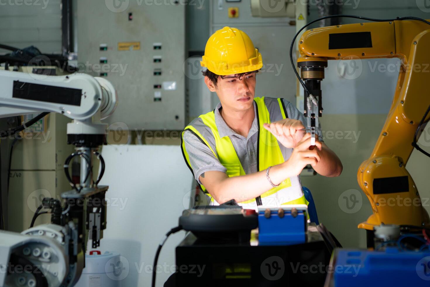 A technician suffers a hand accident while working with a robot arm in a factory with co-workers providing assistance photo