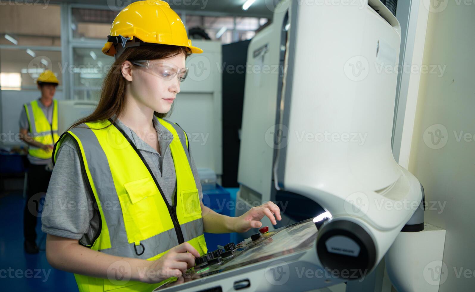Portrait of a female factory worker wearing a hard hat looking at a computer screen used to control production. photo
