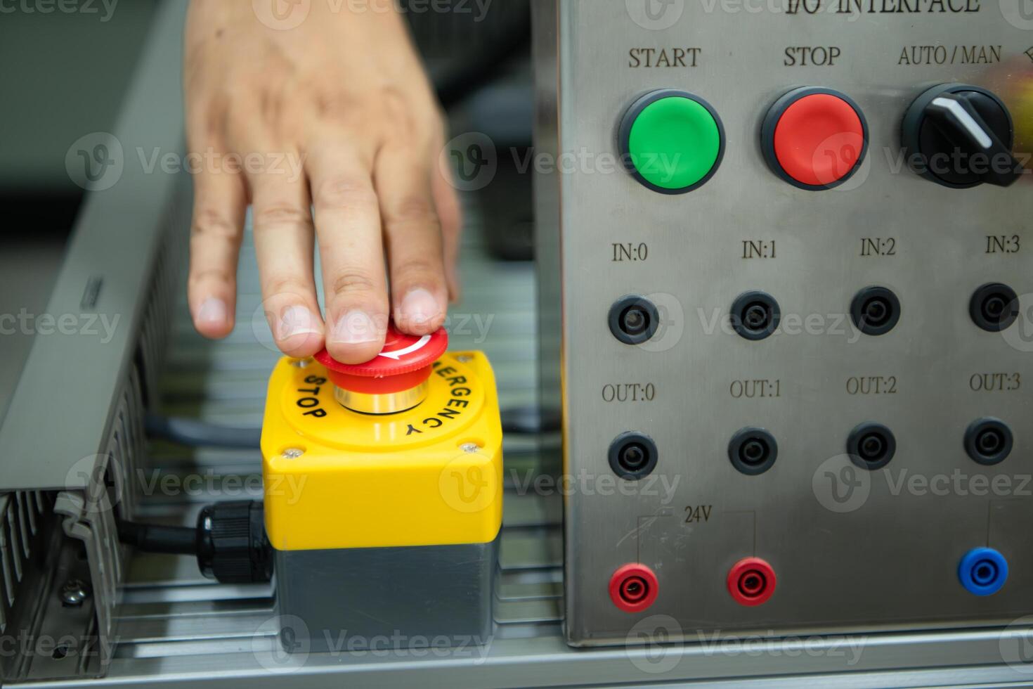 Close-up of hand pressing the stop button on the control panel of an industrial machine. photo
