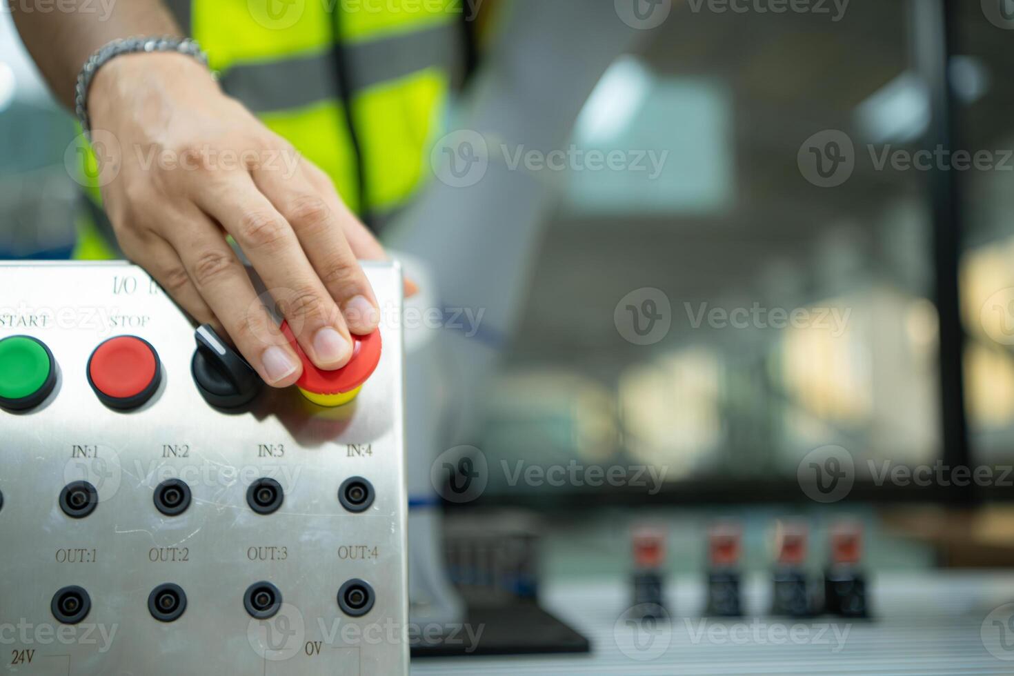 Close-up of hand pressing the stop button on the control panel of an industrial machine. photo