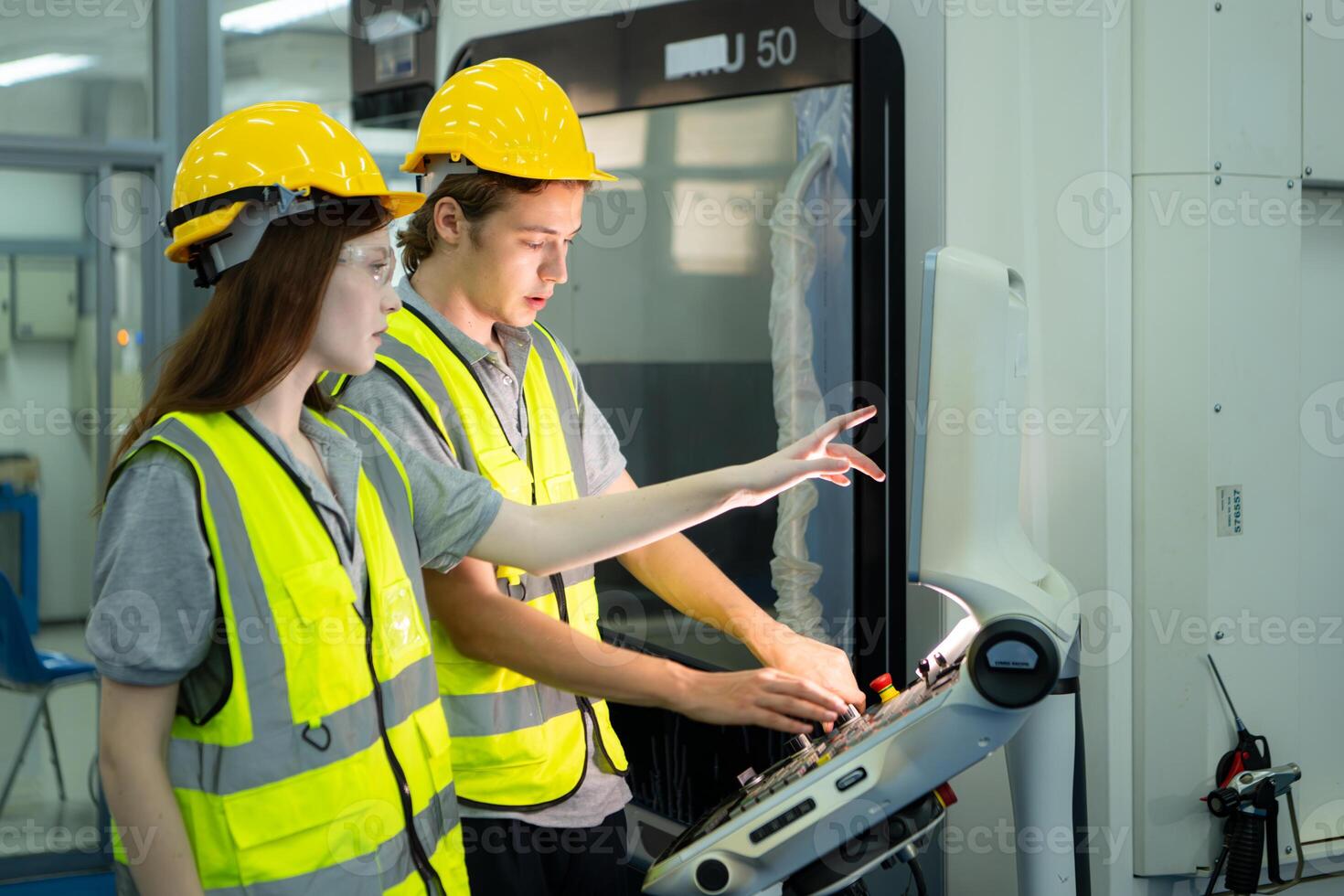 Both of young factory worker wearing a hard hat looking at a computer screen used to control production. photo
