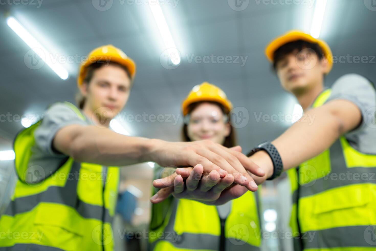 Group of factory workers greeting each other with joint hands together in warehouse photo