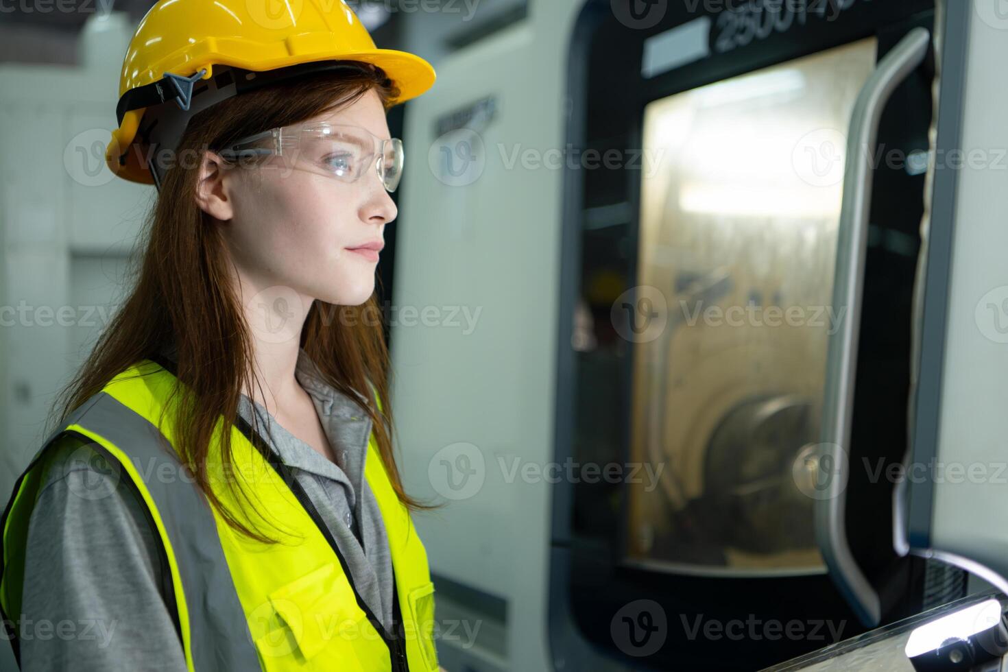 Portrait of a female factory worker wearing a hard hat looking at a computer screen used to control production. photo