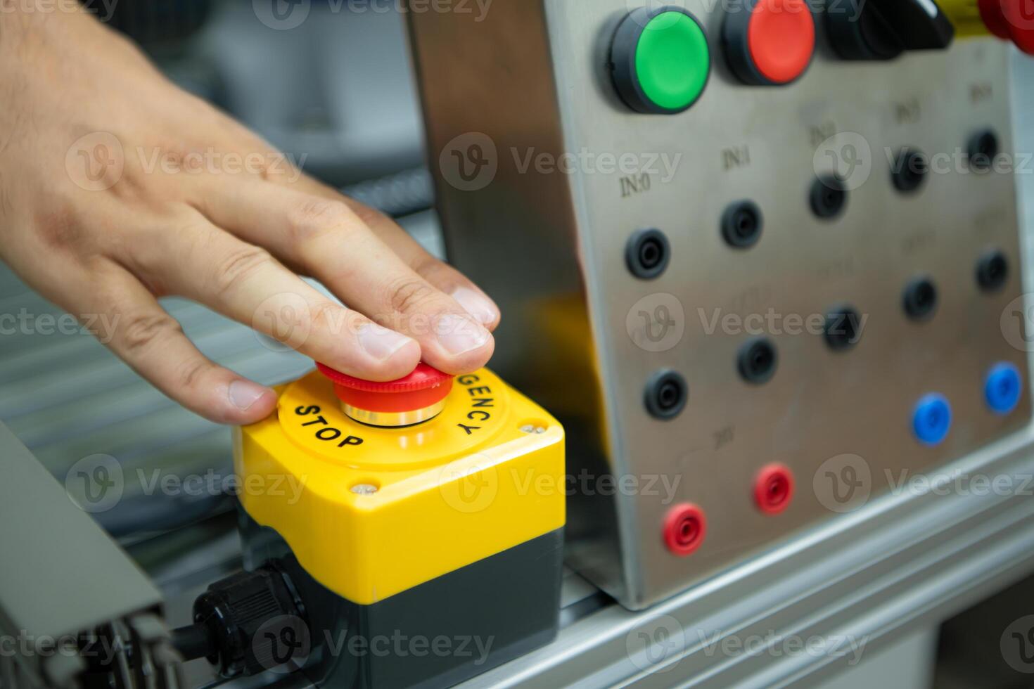 Close-up of hand pressing the stop button on the control panel of an industrial machine. photo