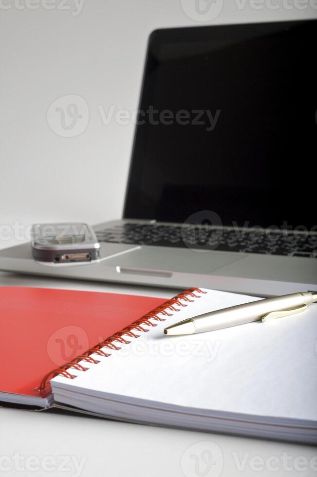 Phone, laptop and empty notebook on the desk photo