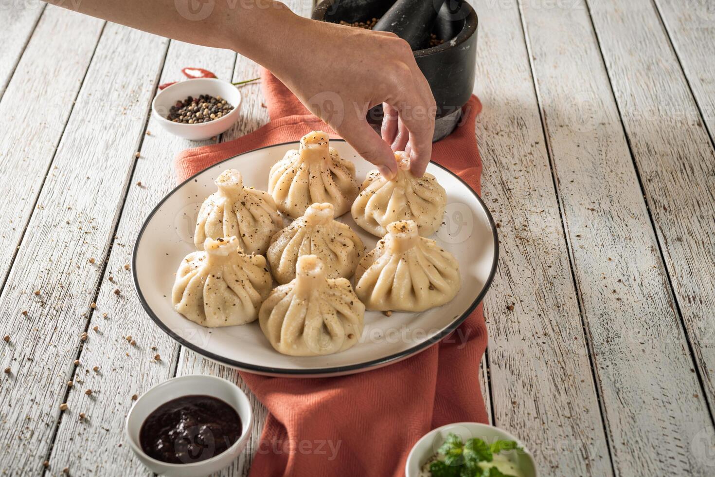Close up to Caucasian khinkali dumplings dish served on plate. Background with ingredients and scattered spices photo