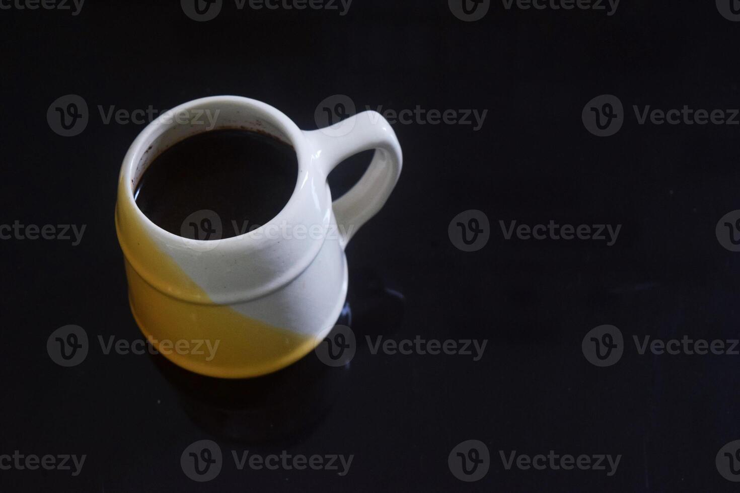 Black coffee in a white and yellow cup on a black ceramic table photo