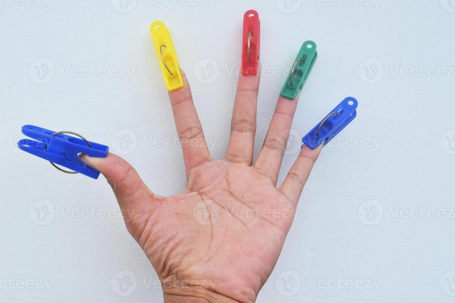 A man's five fingers are clamped by a clothespin photo