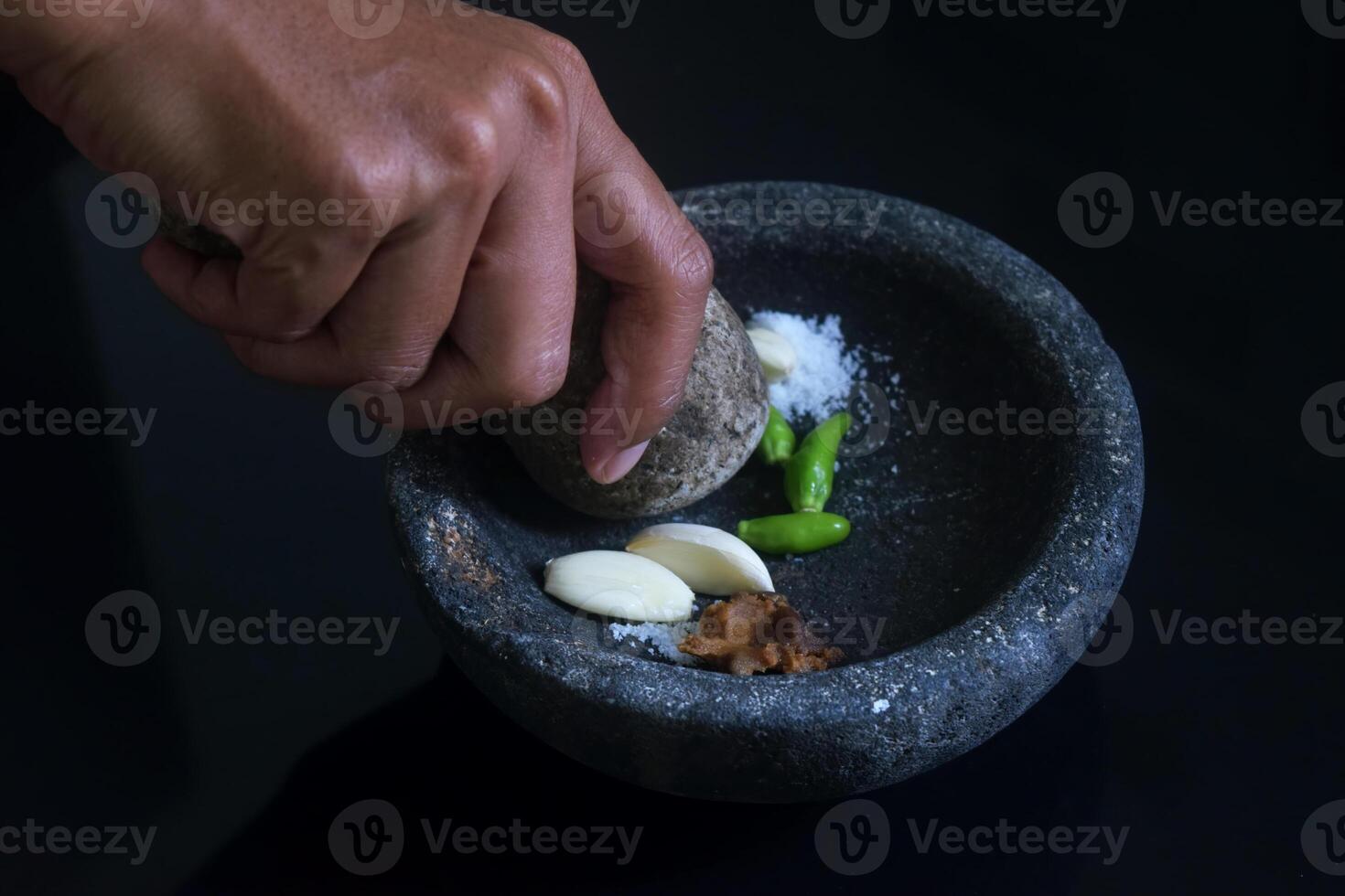 Someone is making chili sauce using a stone blender called Layah photo