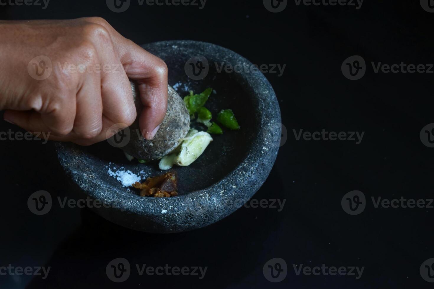 A girl hand is making chili sauce using a stone blender called Layah photo