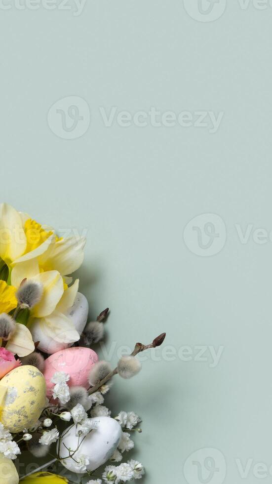 Daffodils, easter eggs and willow on green background with copy space. Easter greeting card template vertical format photo