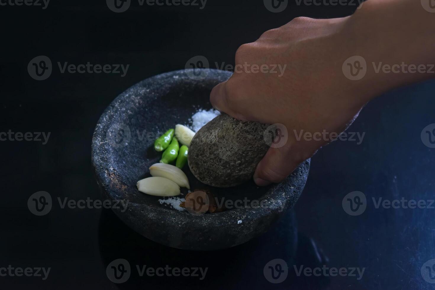 Someone is making chili sauce using a stone blender called Layah photo