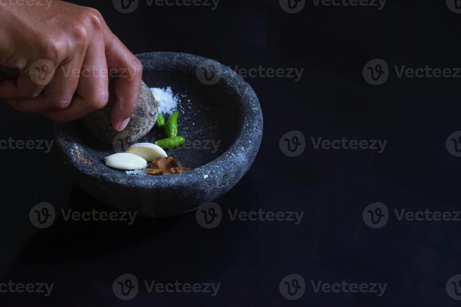 A girl hand is making chili sauce using a stone blender called Layah photo