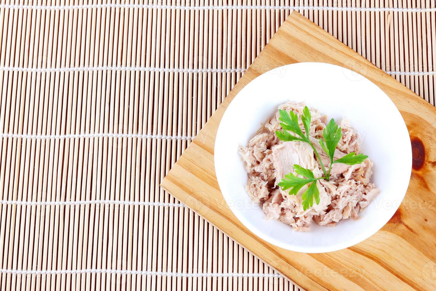 canned tuna in ceramic bowl on wooden cutting board top view photo