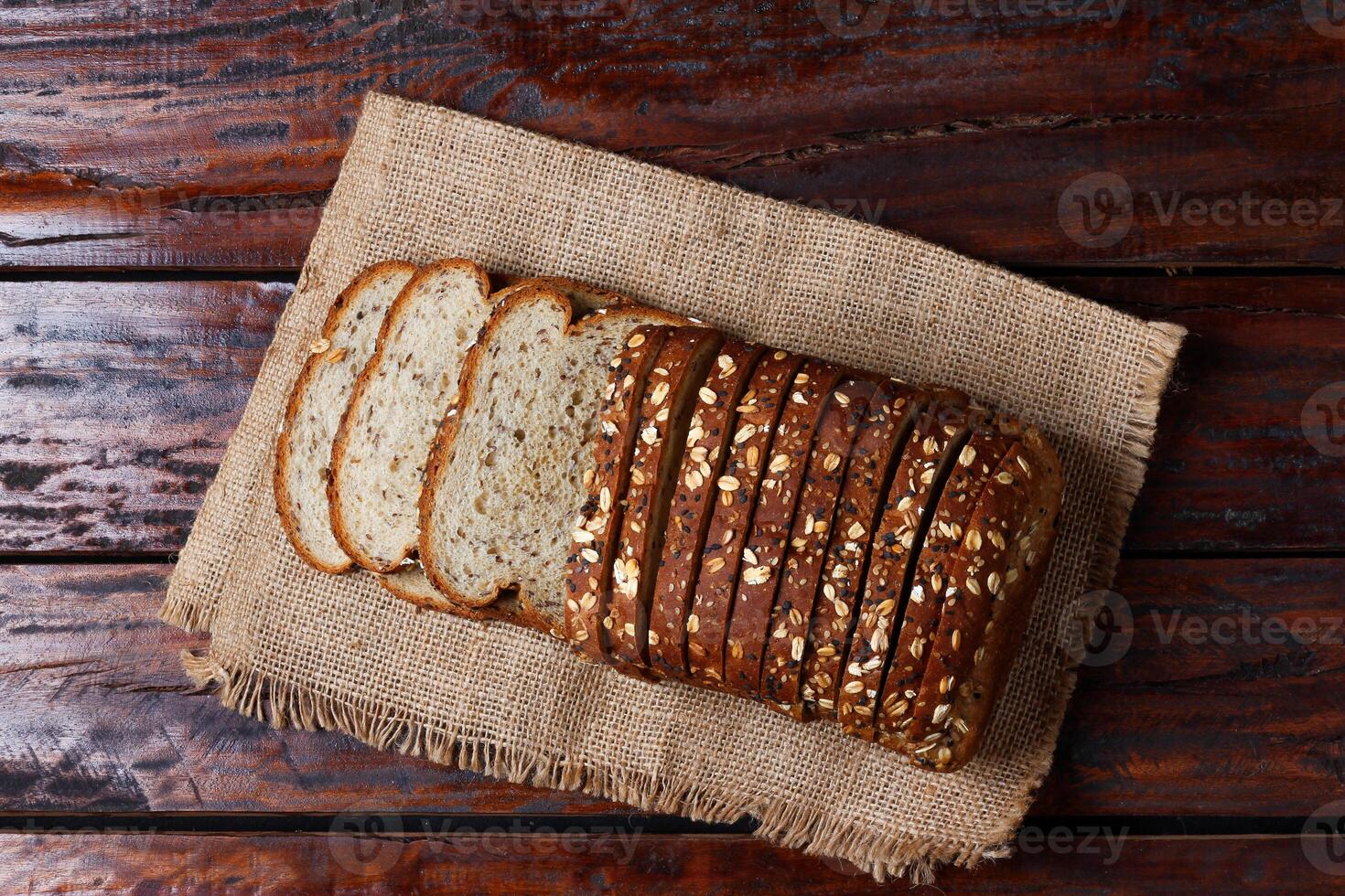whole wheat bread with grains and seeds sliced on wooden table photo