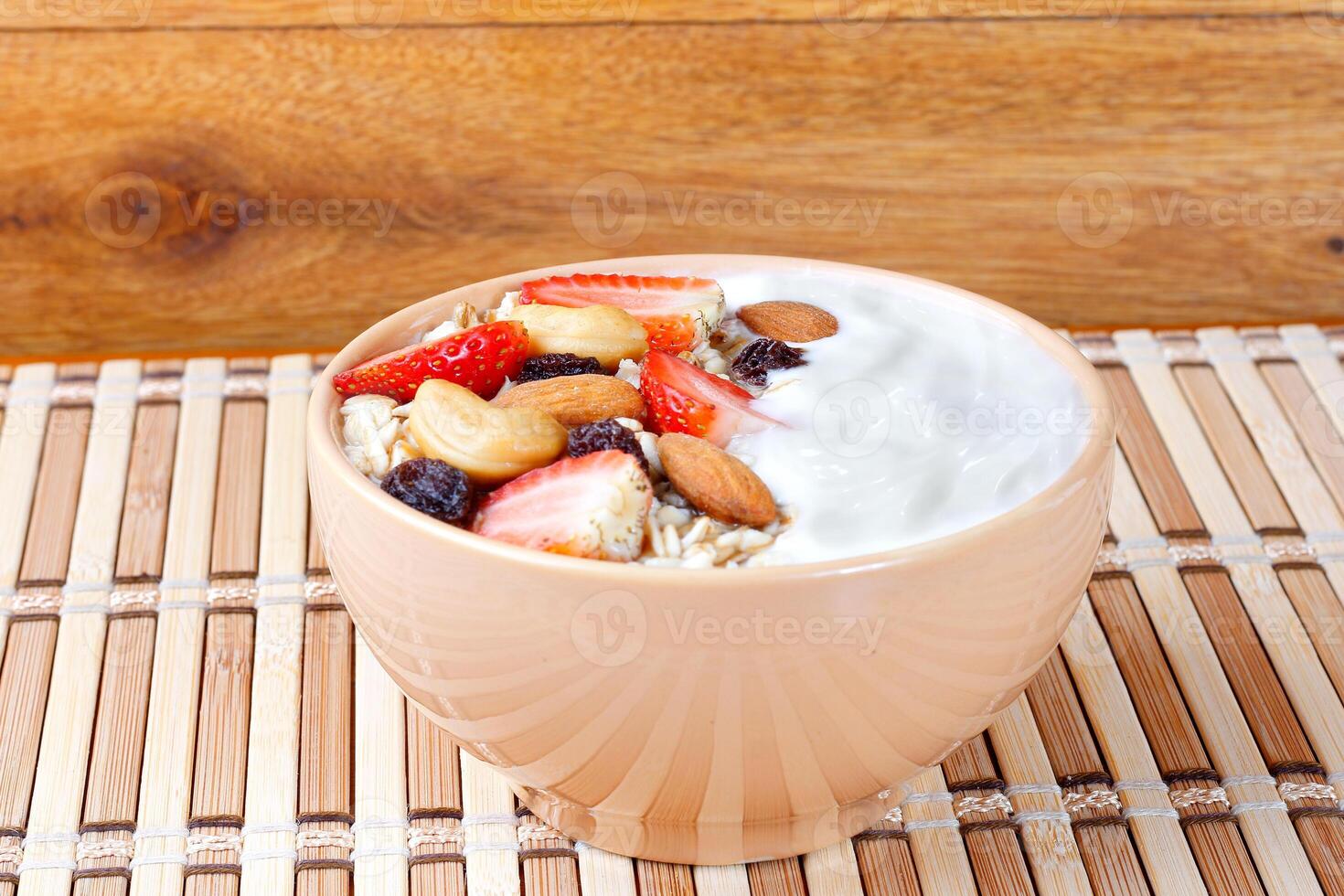 natural yogurt with homemade granola, strawberries and nuts in ceramic bowl on a table top view photo