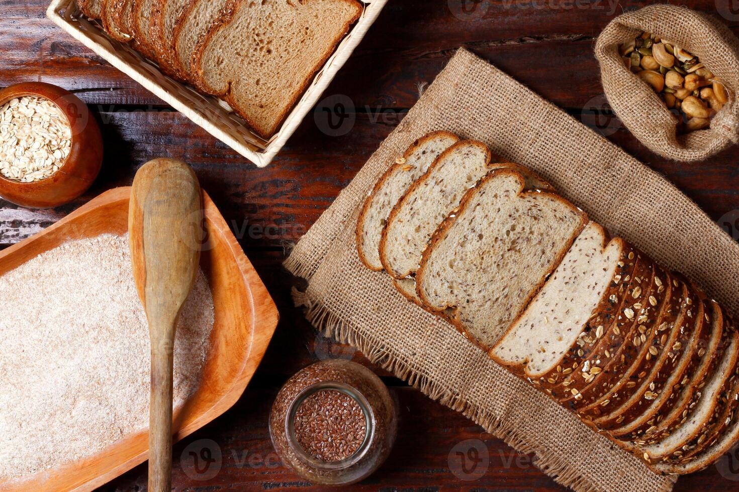 whole wheat bread with grains and seeds sliced on wooden table photo