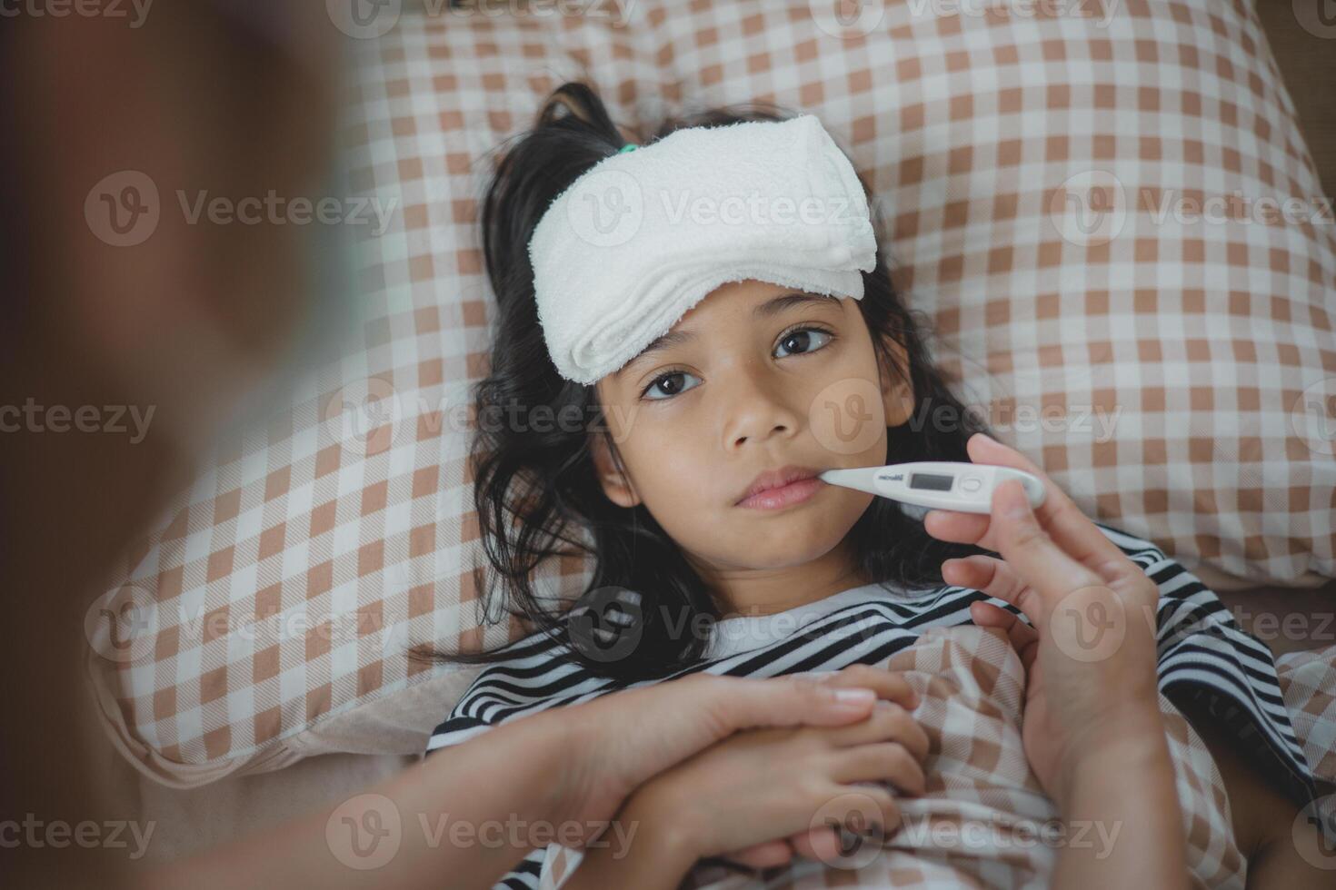 un joven niña es siendo comprobado para un fiebre por un mujer foto