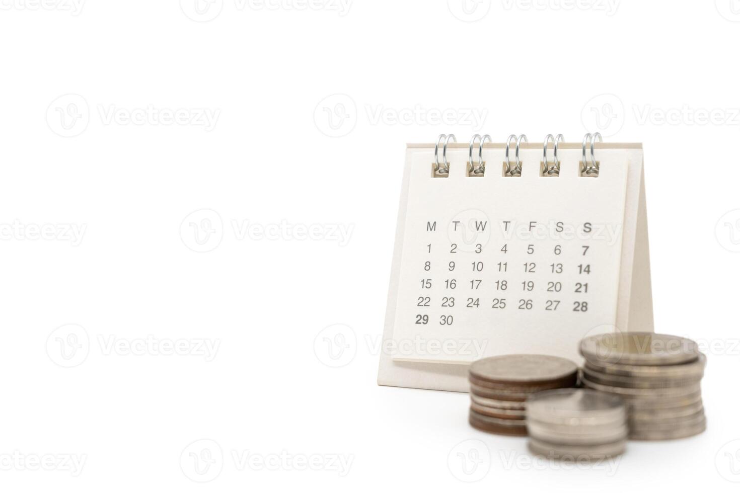For payday loan concept. Desk calendar and blurred stack of coins in isolated background. Business, finance, savings money, wages, payroll or accounting concept photo