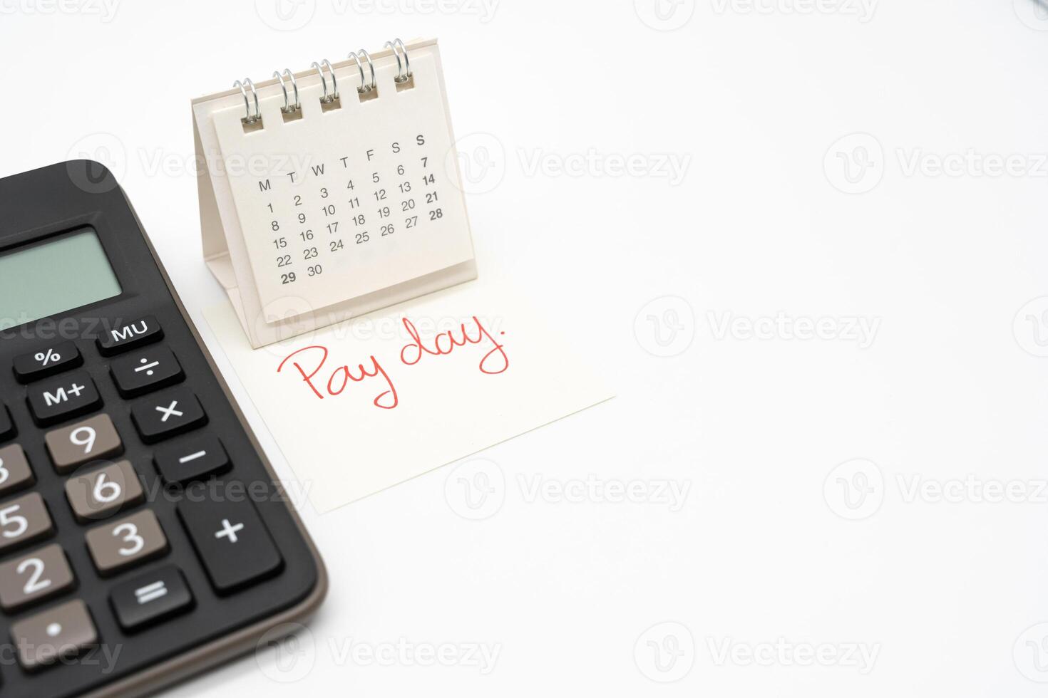 For payday concept. Desk calendar, calculator and paper note in isolated background. Business, finance, savings money, wages, payroll or accounting concept. photo