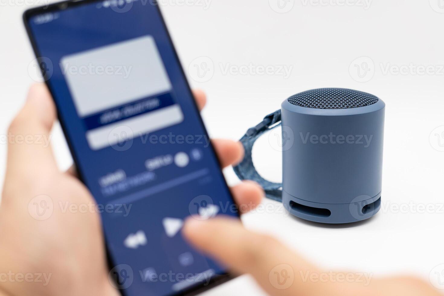 Hand using phone connecting portable speaker. Using bluetooth speaker with smart phone. photo