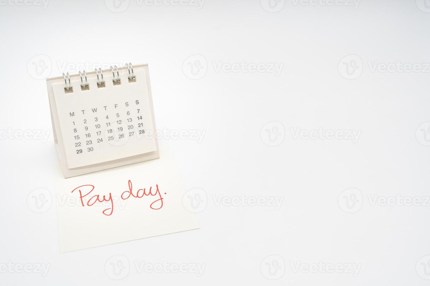 For payday concept. Desk calendar and paper note in isolated background. Business, finance, savings money, wages, payroll or accounting concept. photo